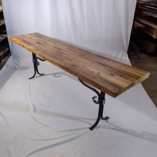 This one-of-a-kind table is designed to enhance the beauty of any living space with its reclaimed oak tabletop and custom wrought iron leg base. The tabletop showcases the beauty of reclaimed material while also possessing the strength and durability needed by sofa tables. The custom wrought iron table legs help support any heavy decorative item that may be placed on the table. These iron legs, with their custom design, add an elegant look that will make the table fit into any modern home.